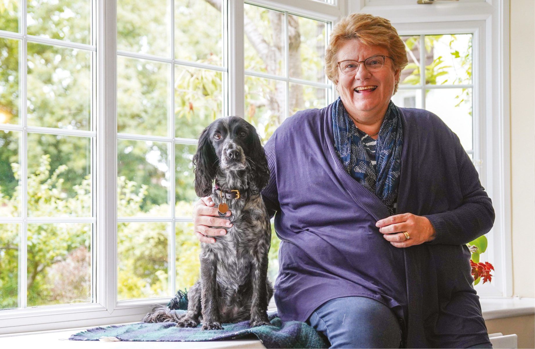 A woman sat next to her hearing dog on a bay window sill A woman sat next to her hearing dog on a bay window sill