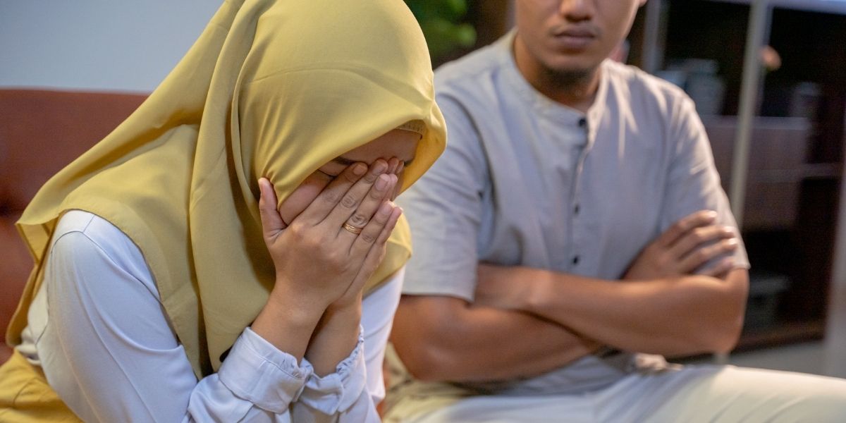 Woman crying, man with folder arms sitting beside her