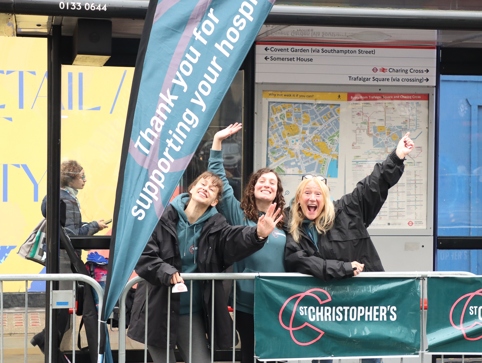Three St Christopher's staff cheering and waving at a cheer station on the Strand.