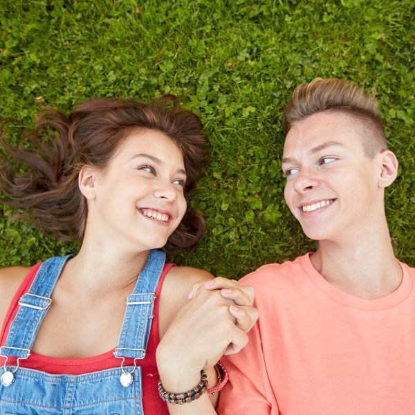 A teenage boy and girl holding hands, smiling