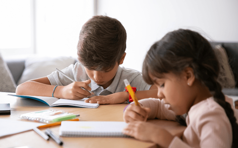 two children sitting at table doing homework